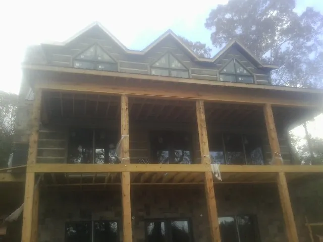 Dormers and porch framing on a large log home under construction — Roof Coating work by our crew in Brewton