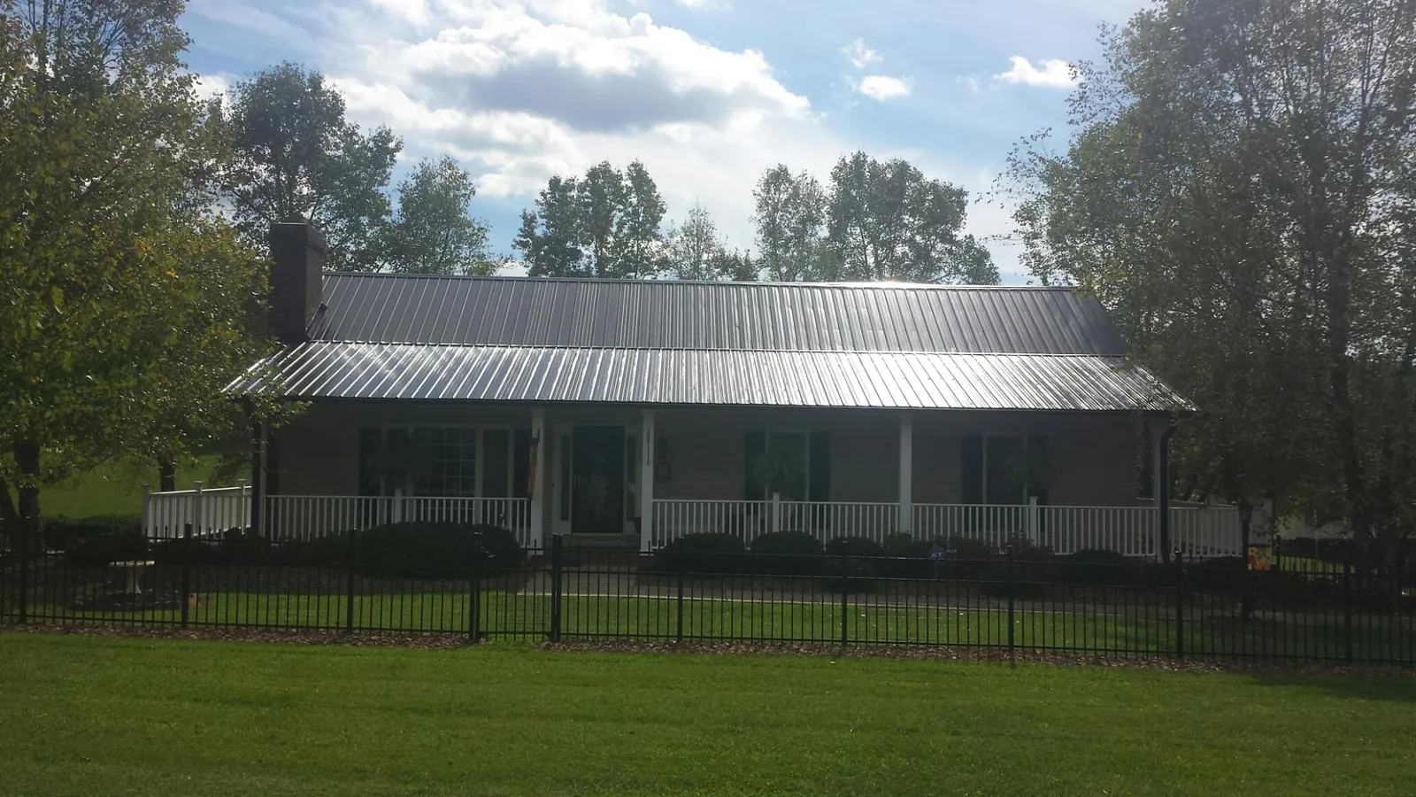 Gray metal roof on a brick ranch with a full width front porch — Gutter Guard Installation work by our crew in Brewton