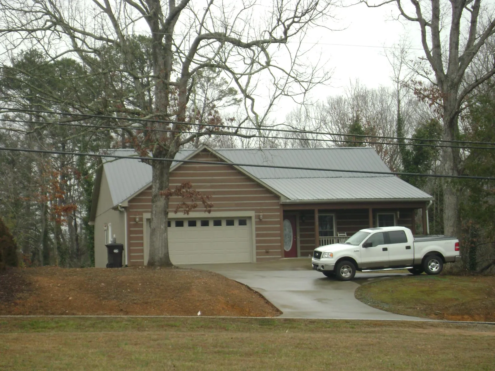Gray metal roof on a log sided house with an attached two car garage in Brewton
