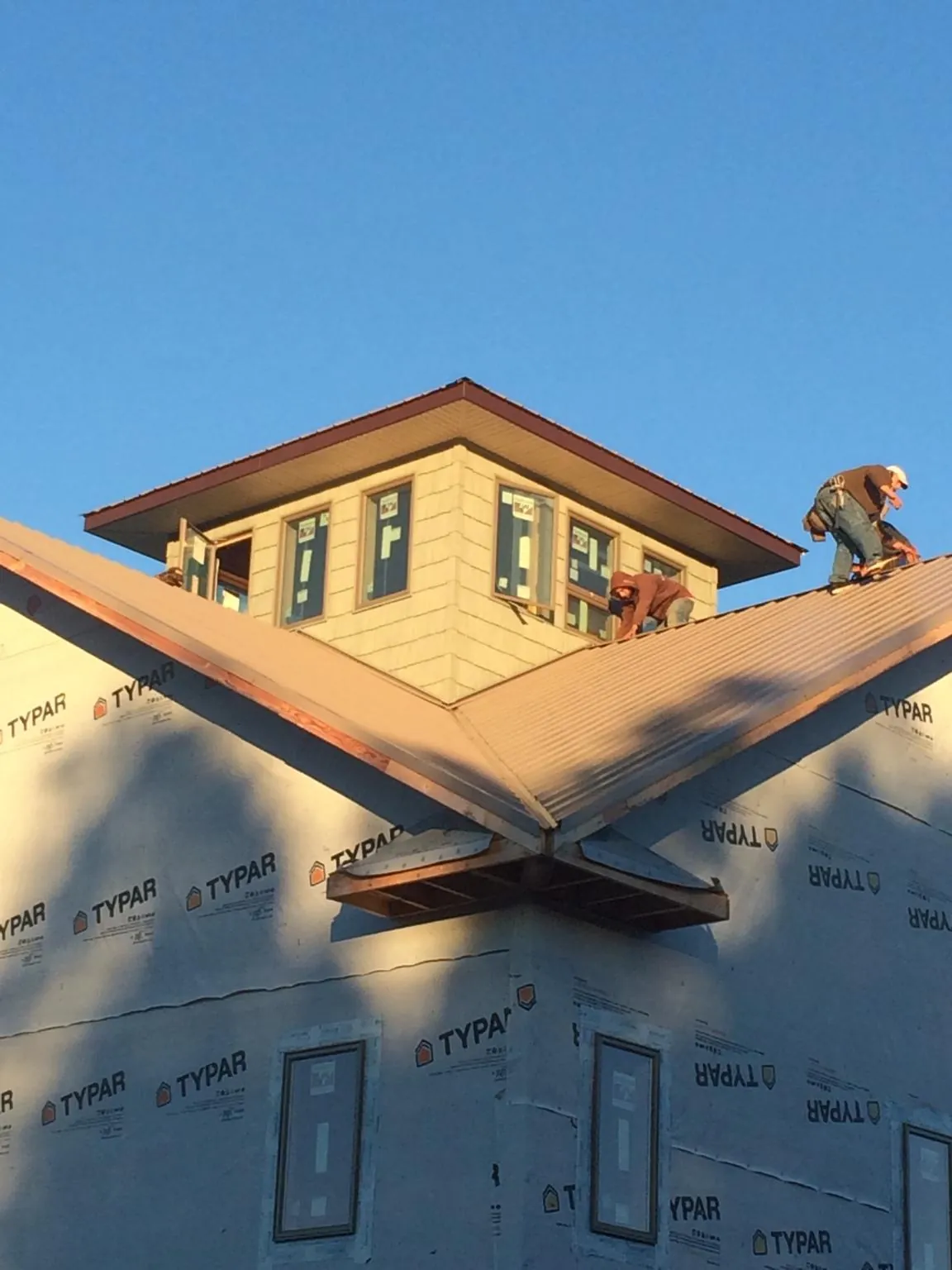 Roofers working around a rooftop cupola on a new metal roof at sunset — Roof Waterproofing in Brewton by Roofing Brothers